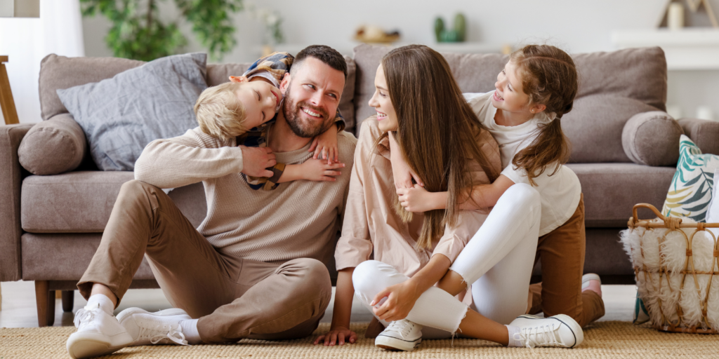 Family Of 4 Spending Time Together In Living Room - HRV vs. ERV: Selecting the Ideal Home Ventilation System