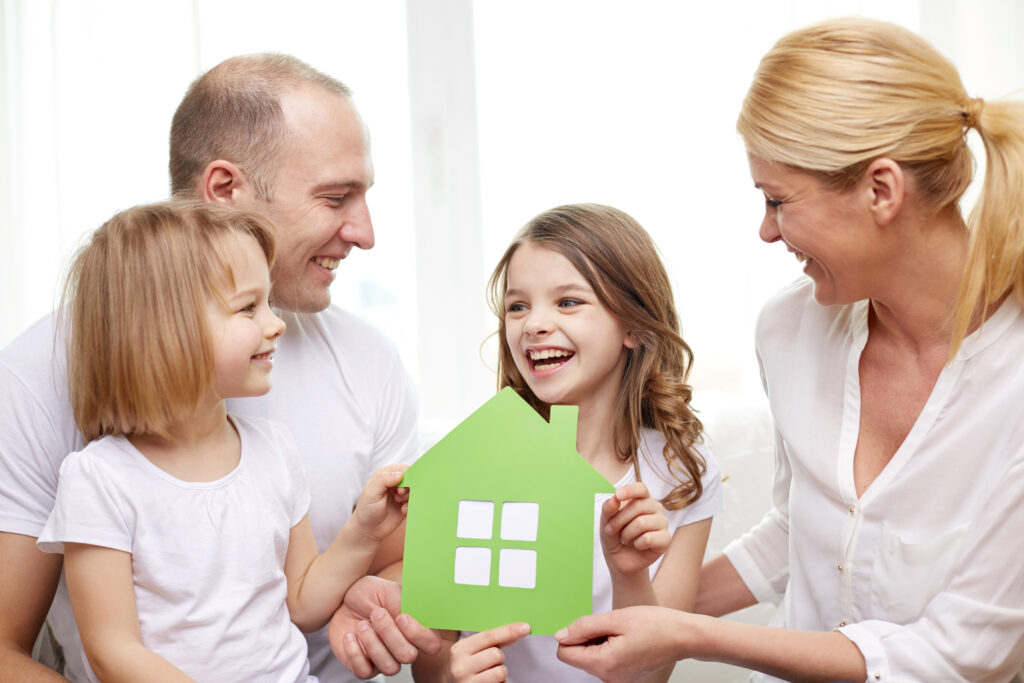 Smiling Parents And Two Little Girls At New Home